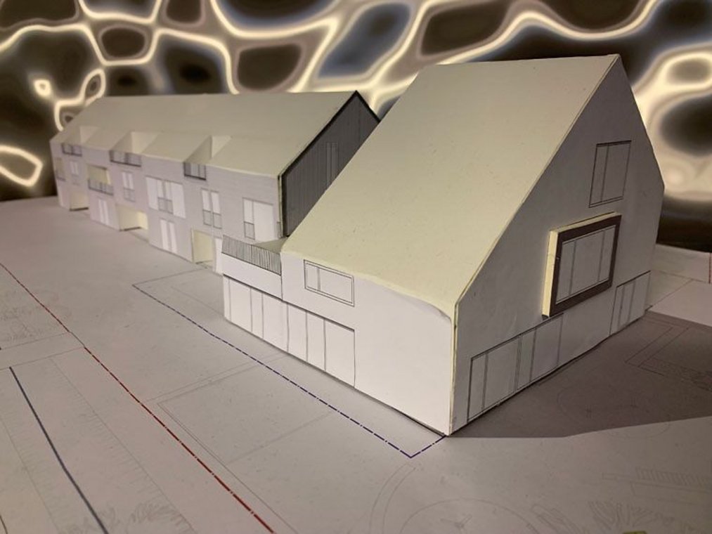 Architekturmodell eines Wohngebäudes auf einem Bauplan