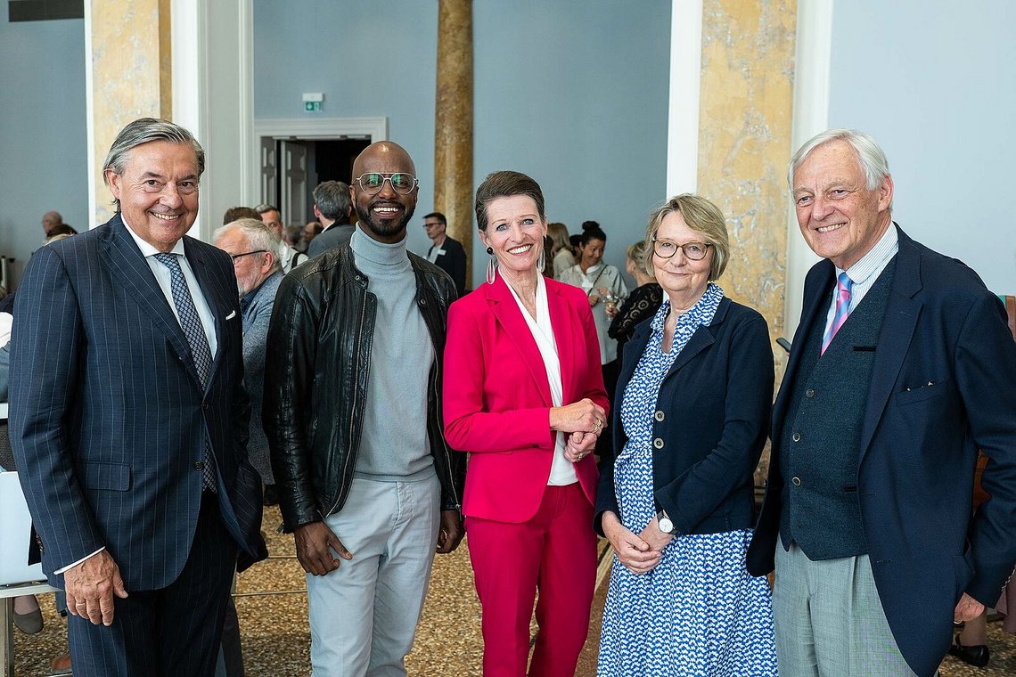 Fünf Gäste beim Empfang im Säulensaal, gemeinsam in die Kamera lächelnd – Stiftungstreffen 2023