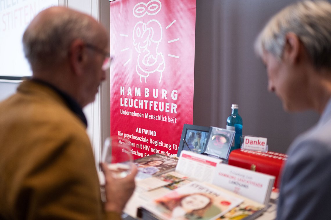 Gäste am Infostand von „Hamburg Leuchtfeuer“ mit Informationsmaterial – Stiftungstreffen 2023