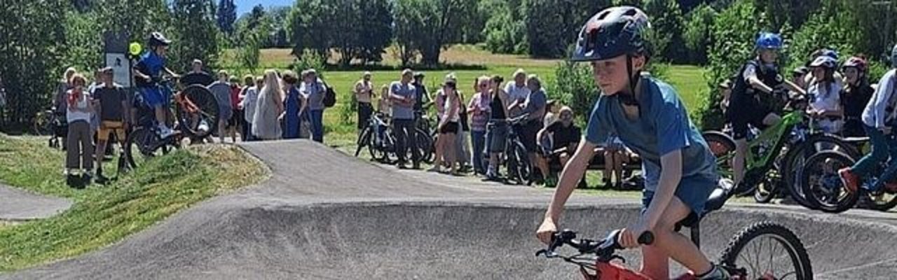 Junge auf dem Mountainbike an einer Pumptrack-Strecke mit Publikum