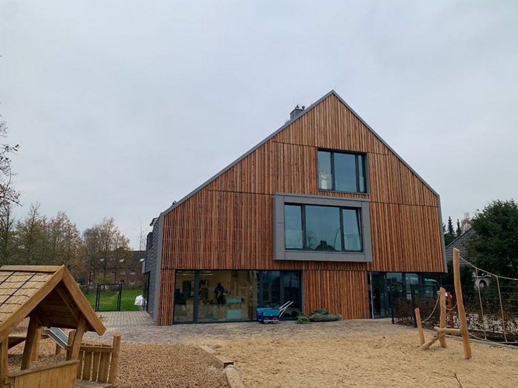Modernes Holzgebäude mit Satteldach und Spielplatz im Vordergrund