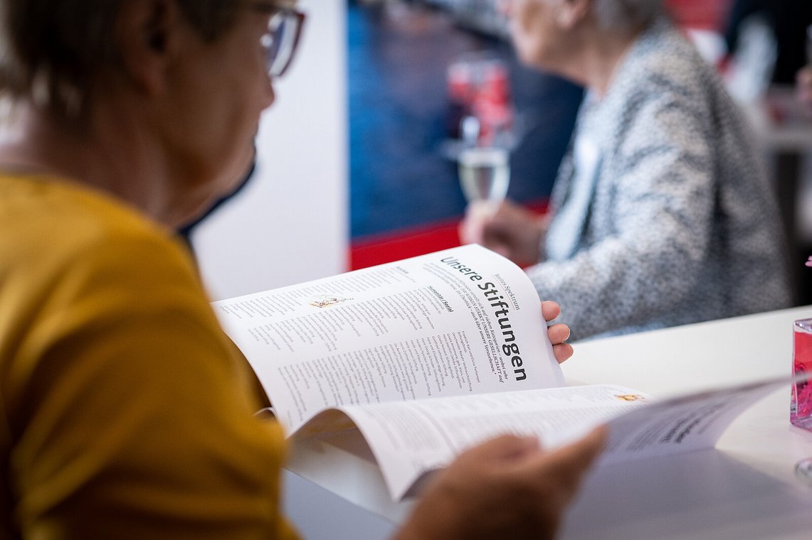 Gast blättert in der Broschüre „Unsere Stiftungen“ – Stiftungstreffen 2023