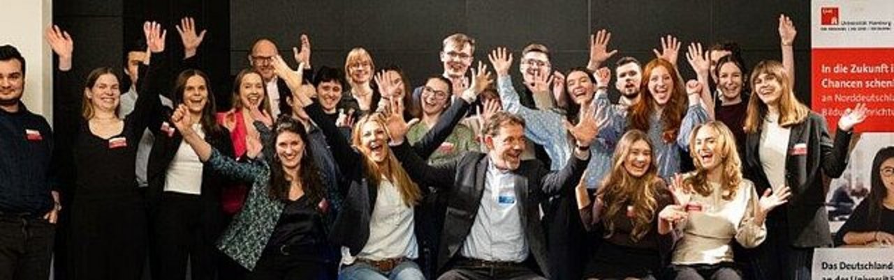 Große Gruppe junger Menschen jubelt mit erhobenen Armen bei einer Veranstaltung