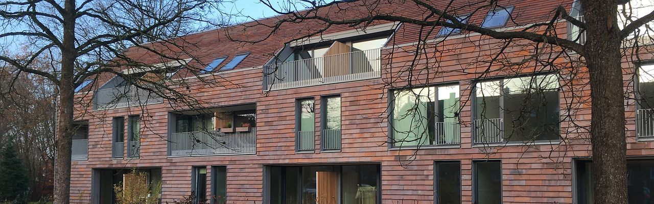 Modernes Wohngebäude aus Backstein mit kahlen Bäumen davor